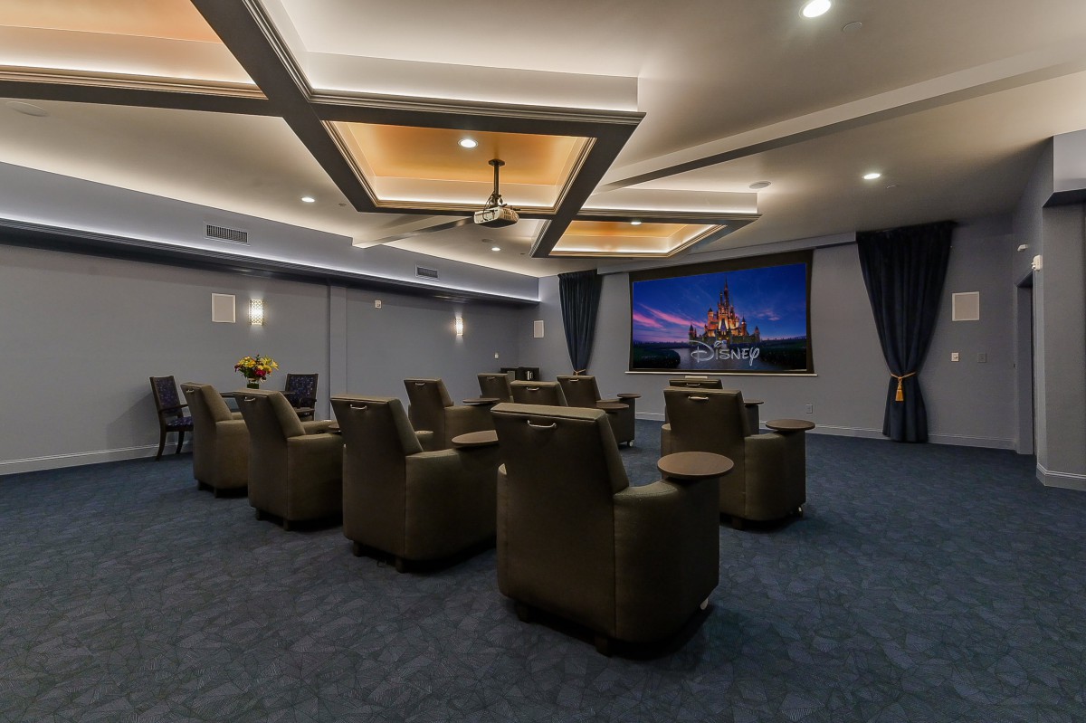 A spacious home theater with comfortable seating and a large screen, featuring modern lighting.