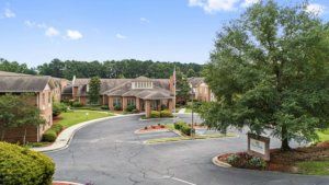 A scenic view of a residential building with a surrounding driveway and trees.