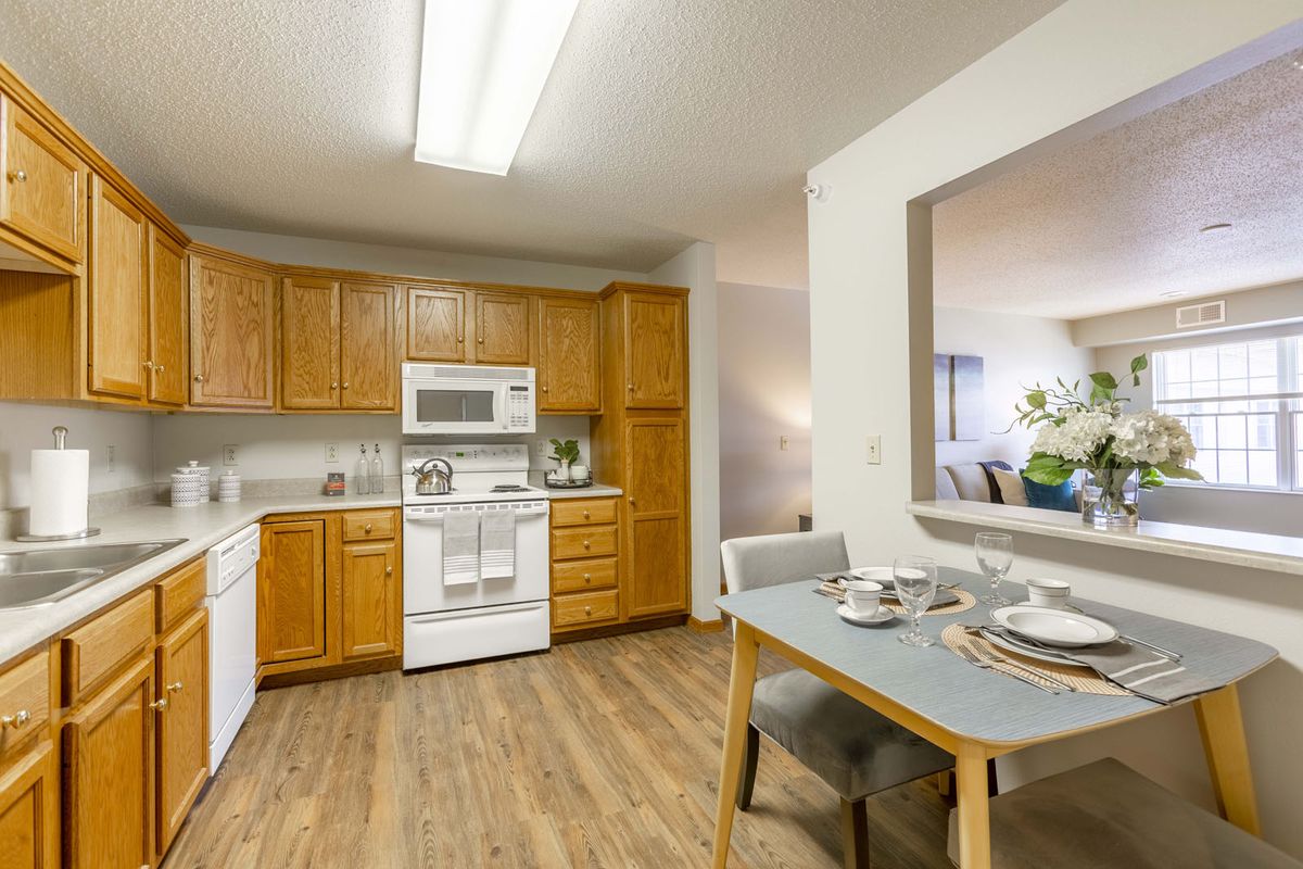 A cozy kitchen and dining area featuring wooden cabinets, white appliances, and a neatly set dining table.