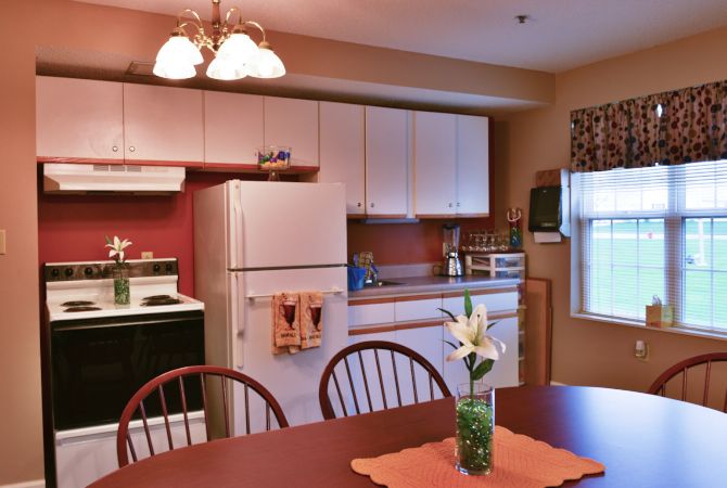 A cozy kitchen with a dining table and chairs, featuring a refrigerator and stove.