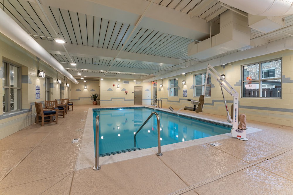 An indoor swimming pool area with seating and bright lighting.
