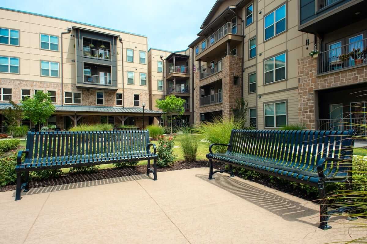 A peaceful courtyard featuring benches surrounded by modern apartment buildings.