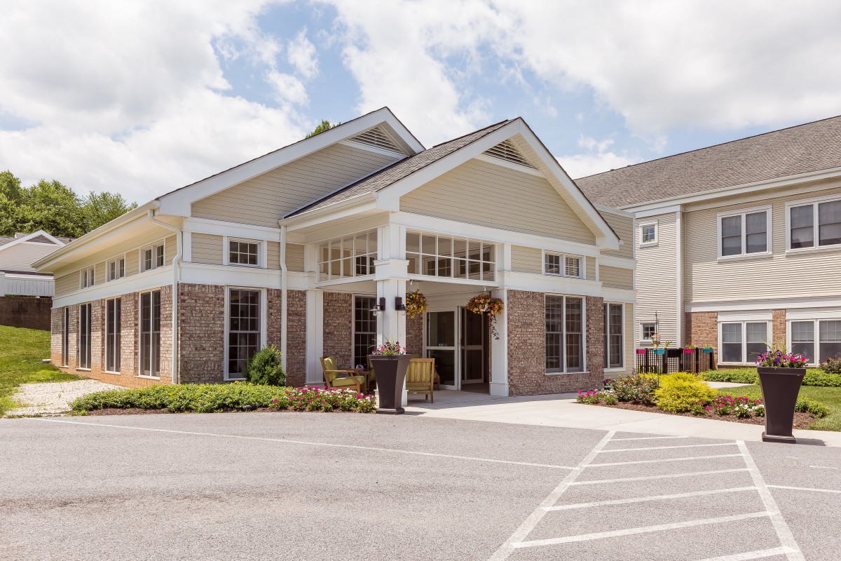 Front view of a building entrance with a landscaped area and parking spaces.