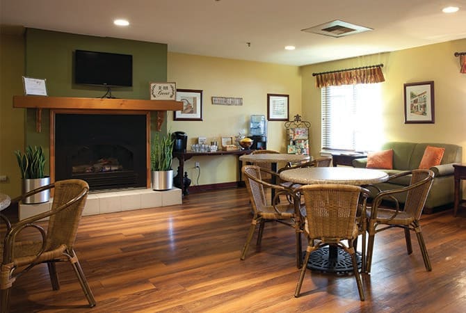 A cozy living room with a fireplace, tables and chairs on a wooden floor.