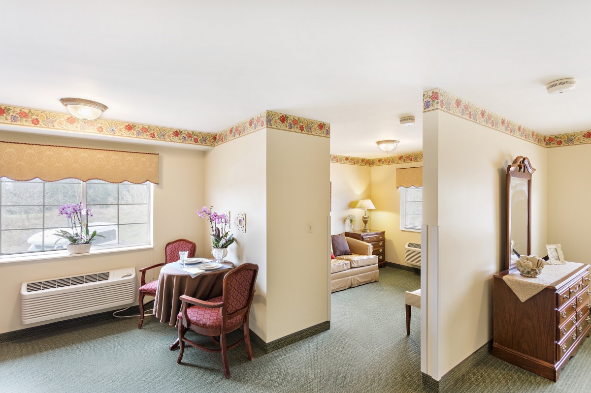 A cozy living space featuring a small dining area and connected seating area with neutral decor.