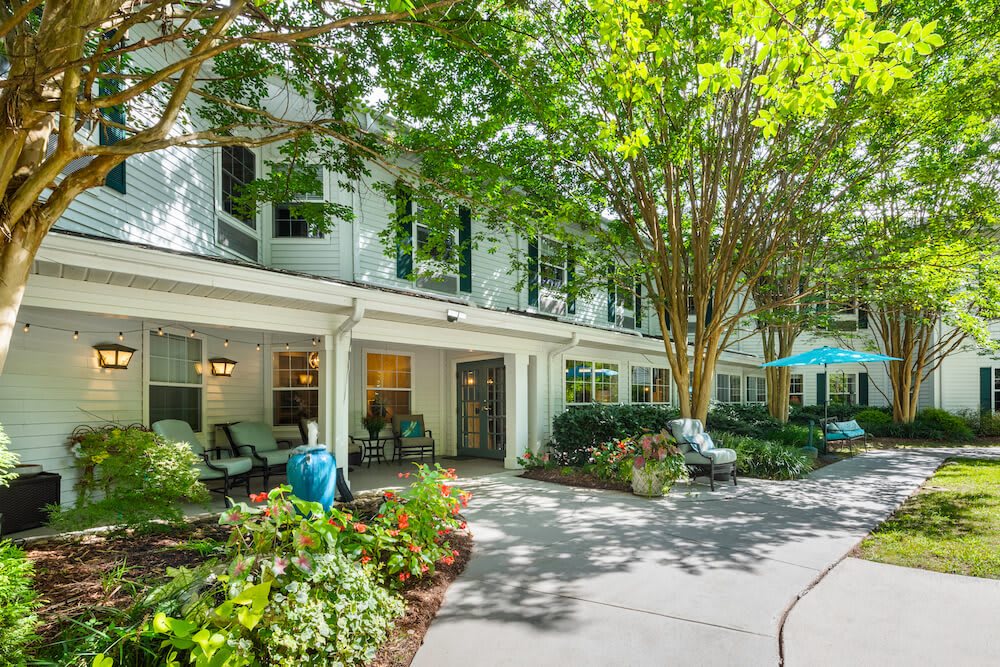 A peaceful residential building surrounded by lush greenery and a shaded pathway.