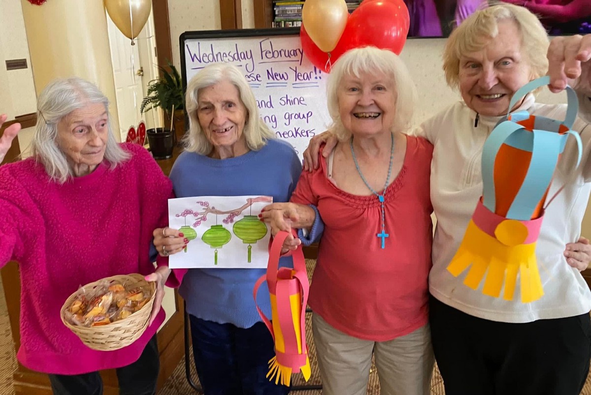 A group of elderly women enjoying a festive celebration with balloons and handicrafts.