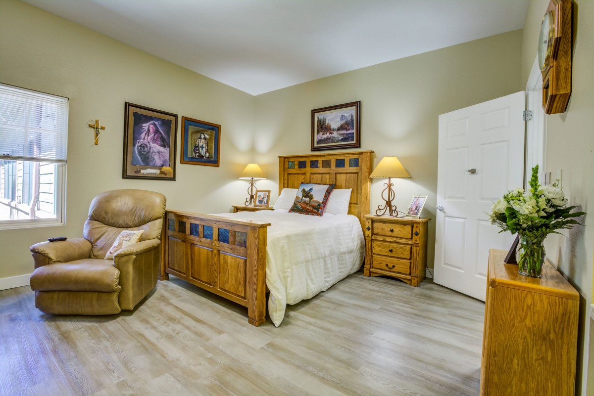A cozy bedroom featuring wooden furniture, decorative wall art, and a comfortable armchair.