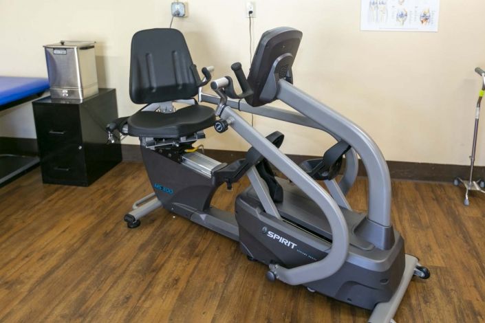 A recumbent exercise bike positioned on a wooden floor in a fitness setting.
