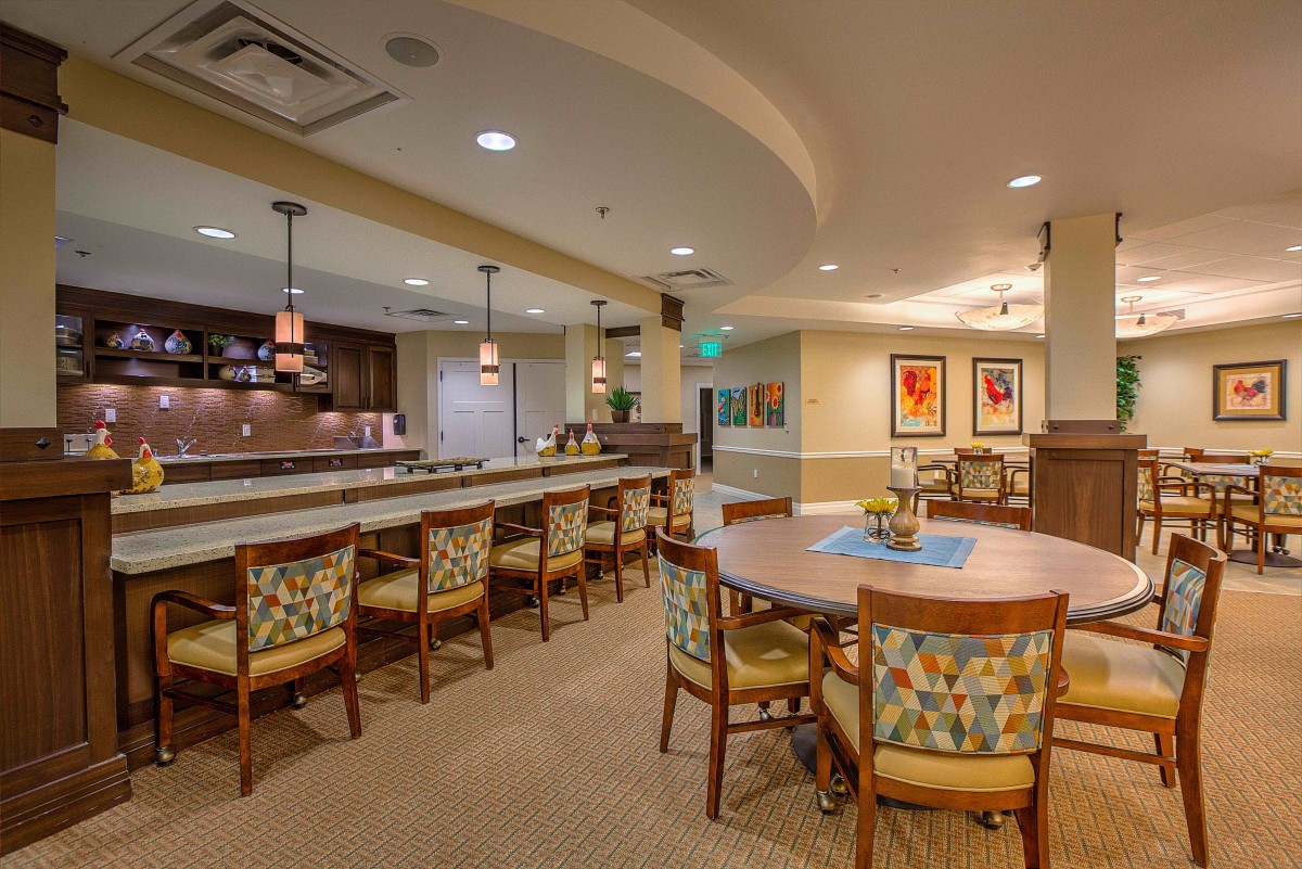 A cozy dining area with a long counter and chairs, featuring warm lighting and artistic decor.