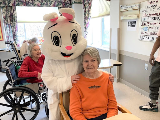 A playful bunny mascot brings joy to elderly residents at a care facility.