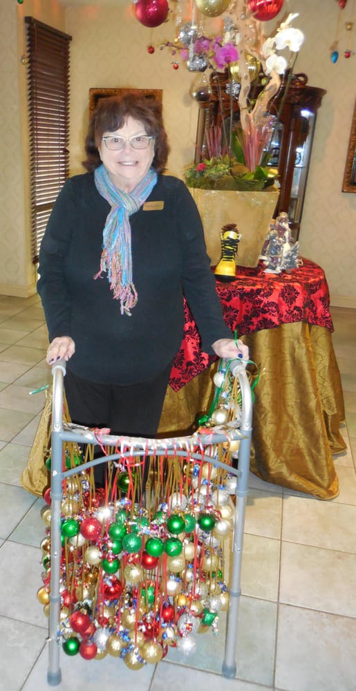 A woman standing indoors with a decorated walker, next to a table with holiday decorations.