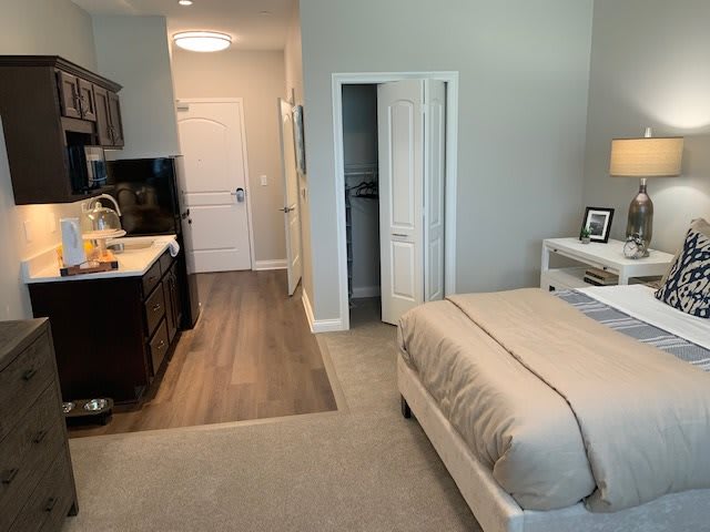 A modern and minimalist apartment featuring a cozy bedroom with an adjacent kitchenette.