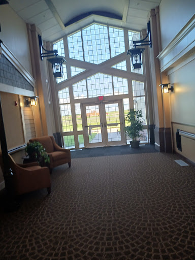 A spacious lobby with large windows allowing natural light, featuring comfortable seating and decorative plants.