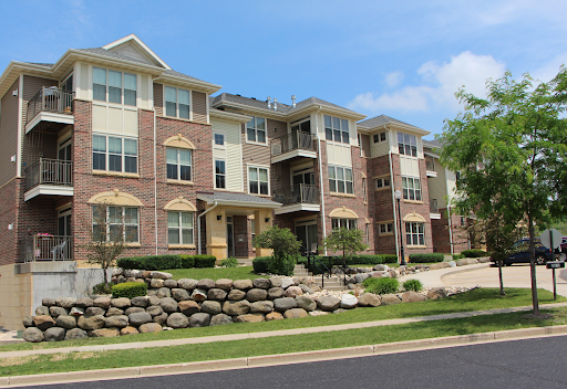 A modern apartment complex featuring multiple levels with brick facades and landscaped surroundings.