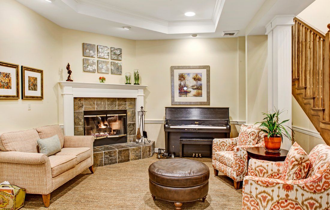 A cozy living room featuring a fireplace, piano, and comfortable seating with decorative artwork on the walls.
