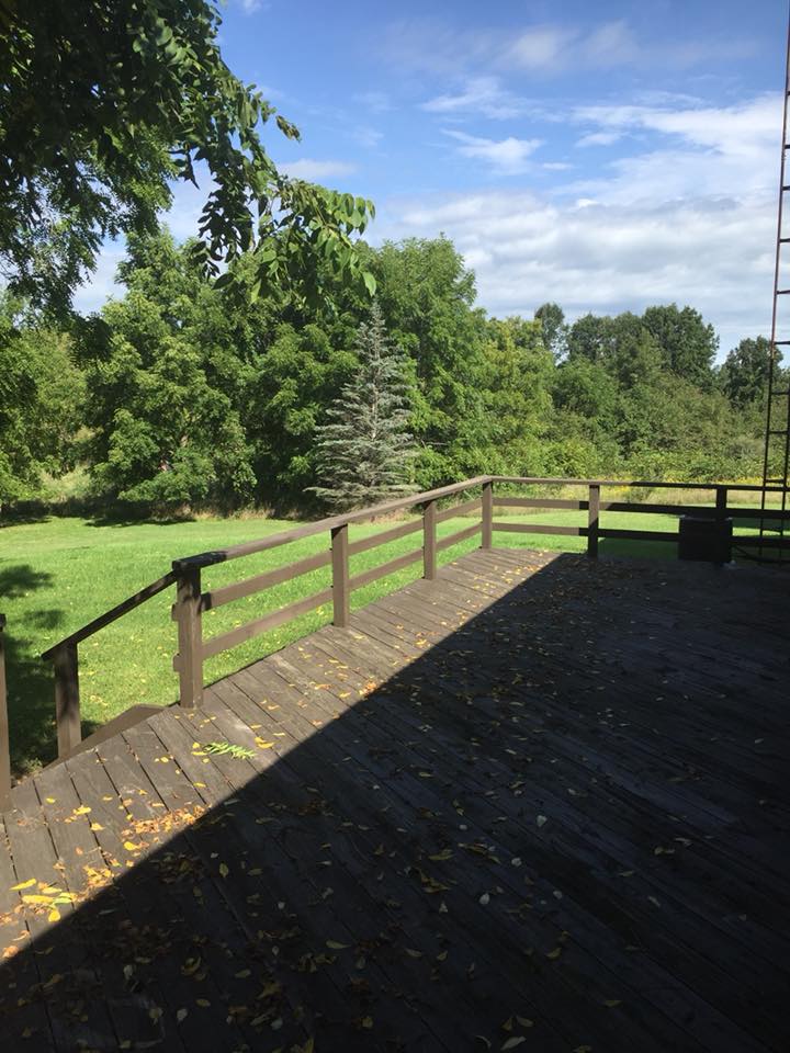 A wooden deck overlooking a lush green landscape under a clear sky.