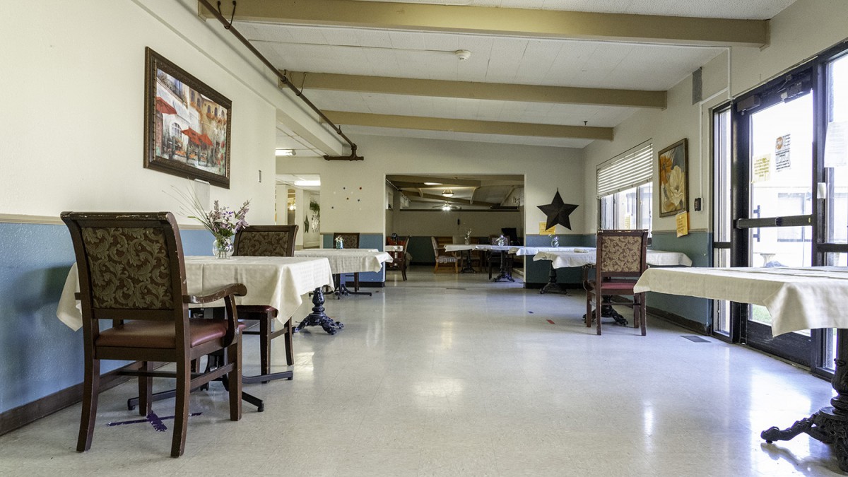 An empty dining area with neatly arranged tables and chairs, decorated with wall art and a star ornament.