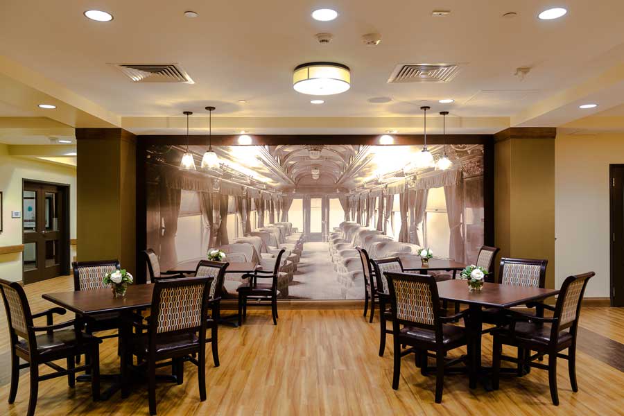 An elegant dining area with tables and chairs, featuring a mural of a classic train interior.