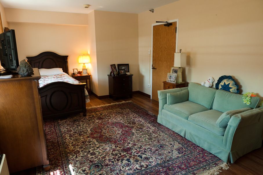A cozy bedroom with a large bed, green sofa, and an ornate rug on the floor.