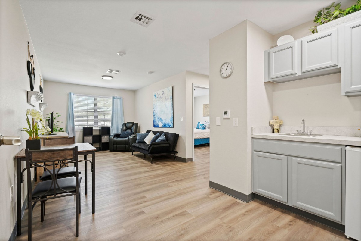 A modern open-concept living area with a dining table, seating, and kitchenette.