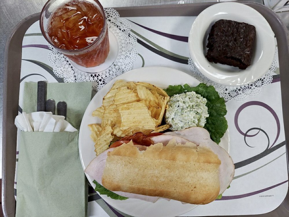 A plate featuring a sandwich, potato chips, and a salad, accompanied by iced tea and a brownie.