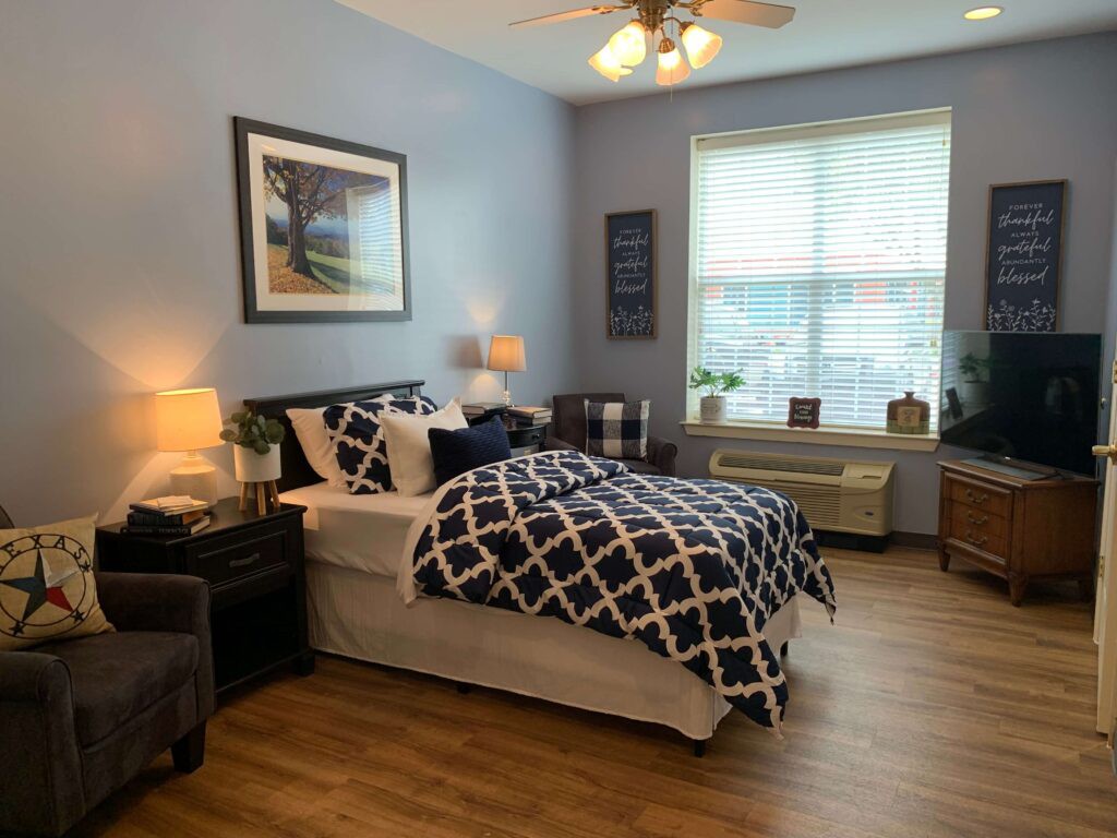 A cozy bedroom with modern decor, featuring a bed with patterned bedding, a large window, and stylish furniture.