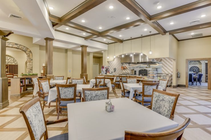 A cozy dining area with neatly arranged tables and chairs, featuring warm lighting and elegant interior design.