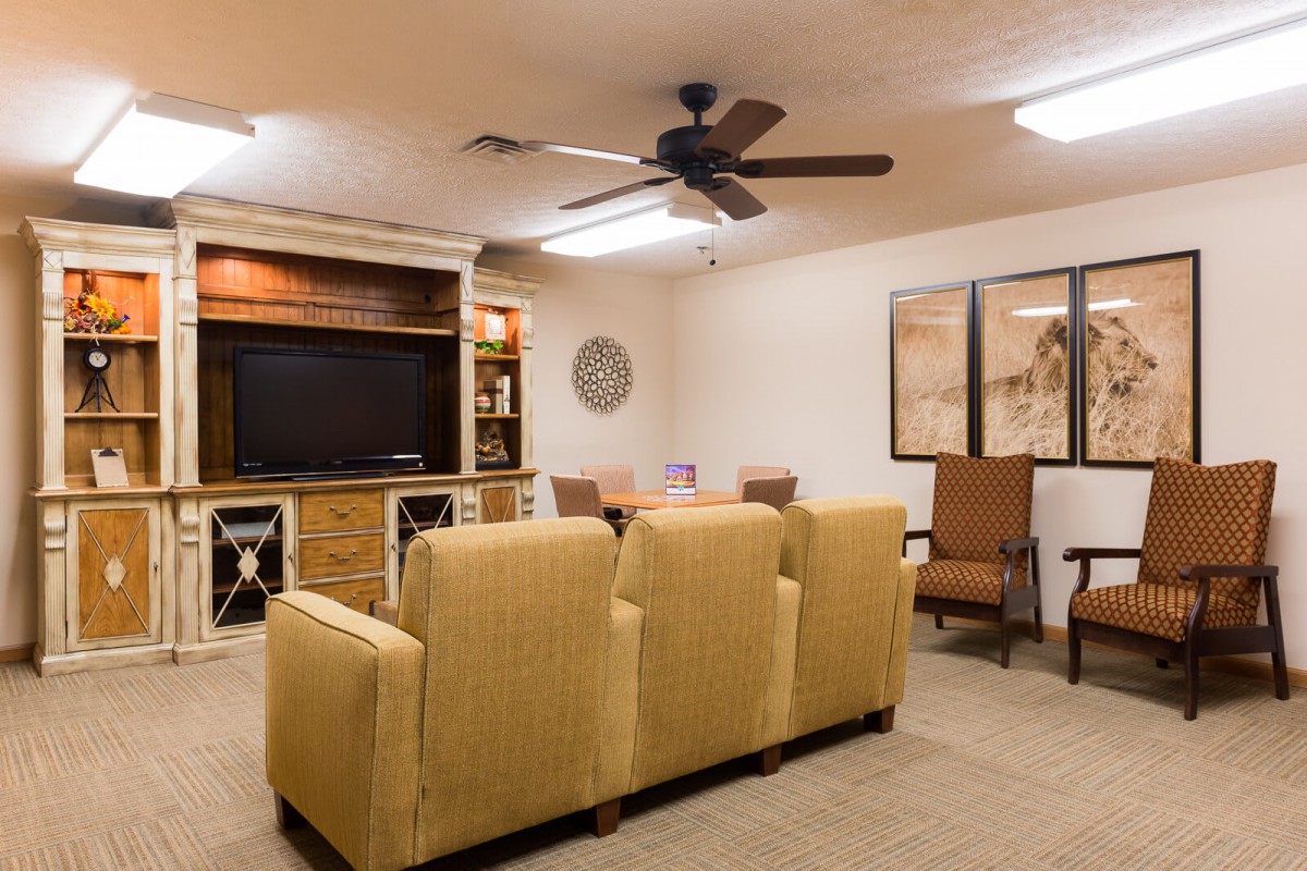 A cozy living room featuring comfortable seating, a large television, and a ceiling fan.