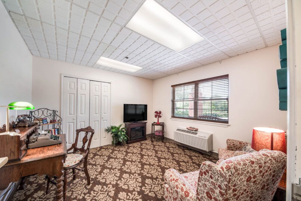 A cozy living room with a patterned carpet, television, and classic wooden furniture.