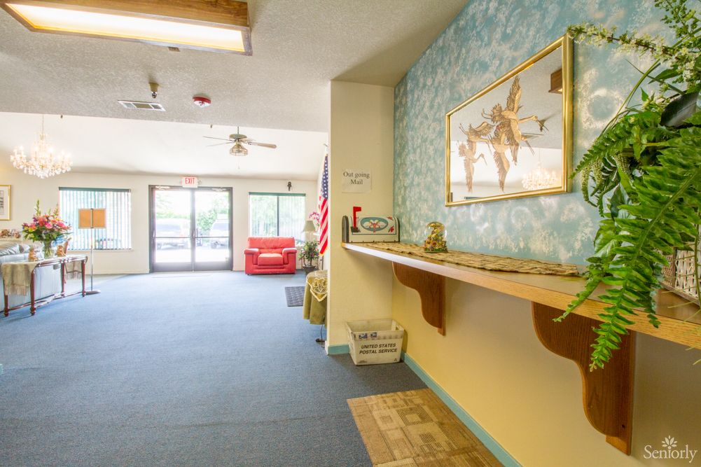 A bright hotel lobby with a blue carpet, decorative artwork on the wall, and a shelf displaying various items.