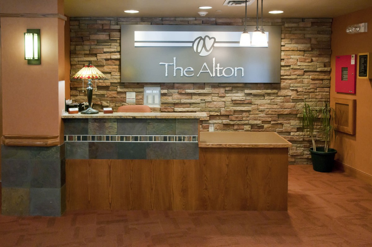A modern reception area with a wooden desk and stone wall backdrop.