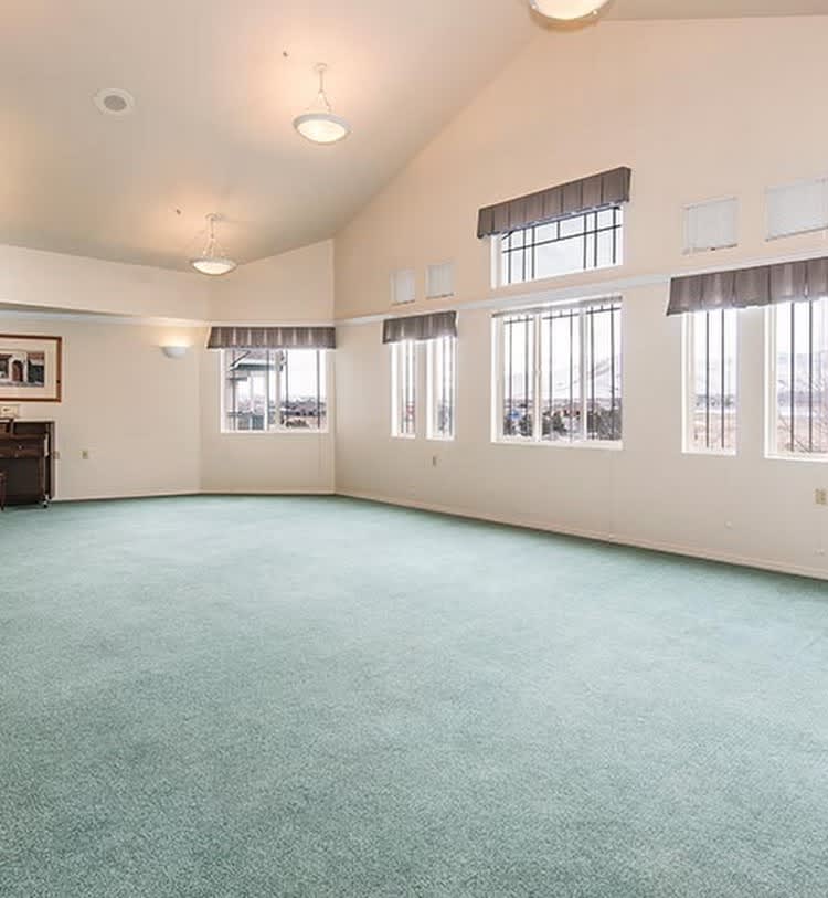 Spacious living room with large windows and green carpet.