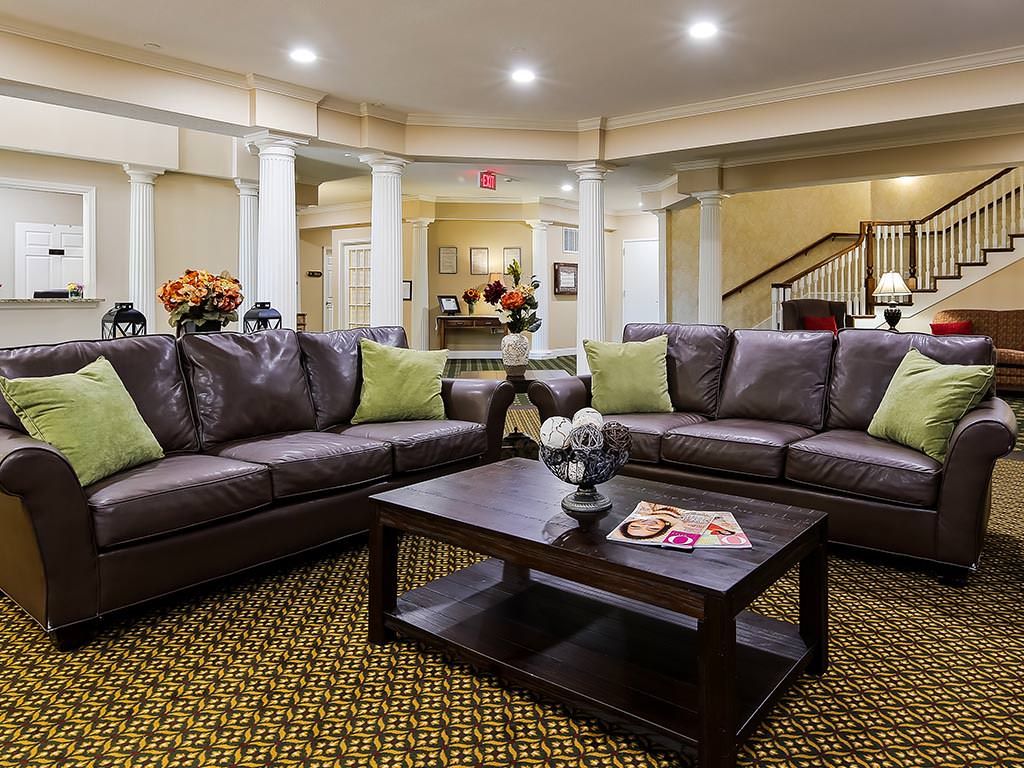 A cozy living room with two dark brown sofas, a wooden coffee table, decorative pillows, and bright overhead lighting.