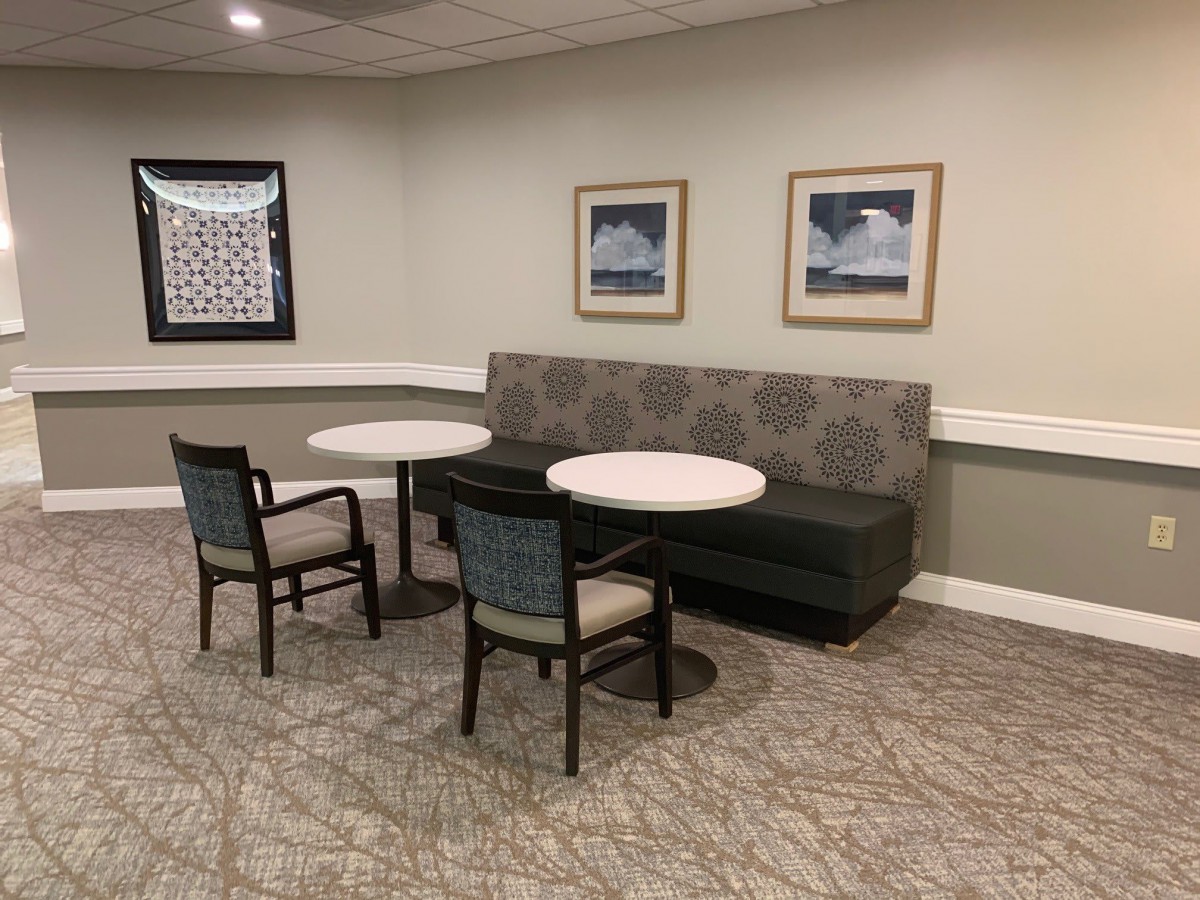 A cozy indoor seating area with tables, chairs, and a couch, complemented by wall art.