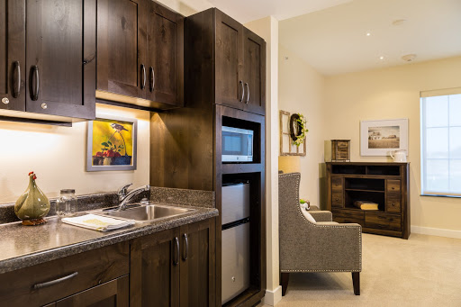 A cozy kitchenette featuring dark wood cabinets, modern appliances, and a comfortable living area.