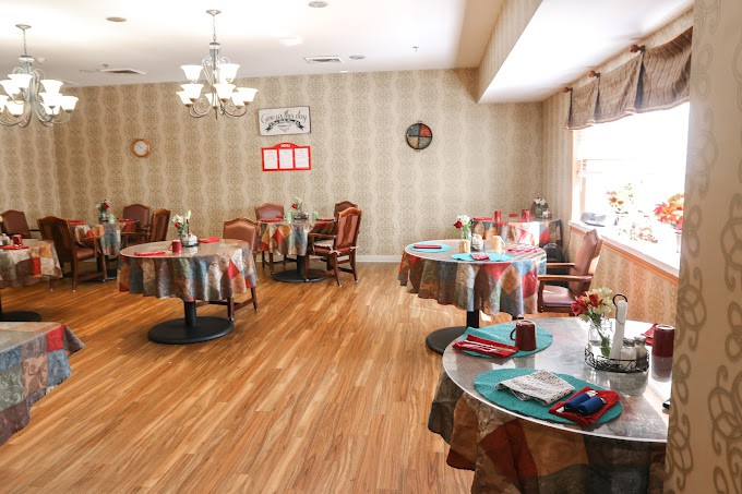 A cozy dining room with elegantly set tables and chairs, featuring warm lighting and classic decor.