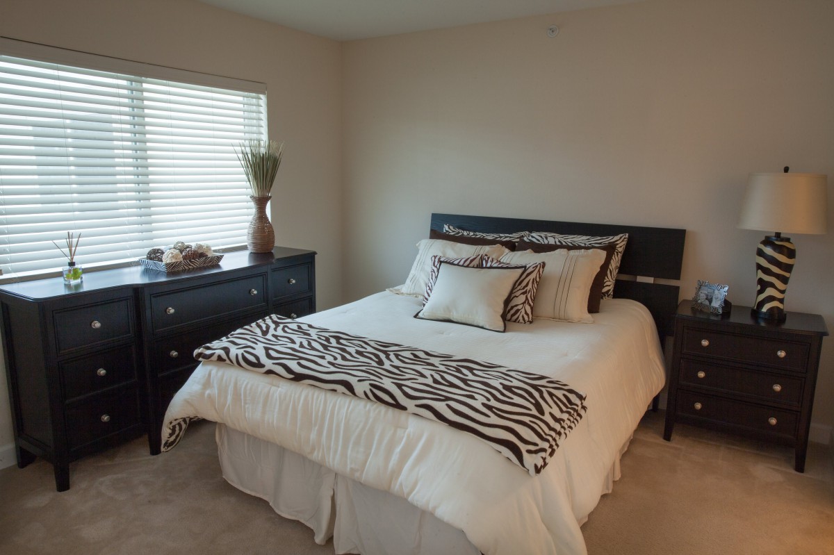 A cozy bedroom featuring a bed with zebra print accents and dark furniture.