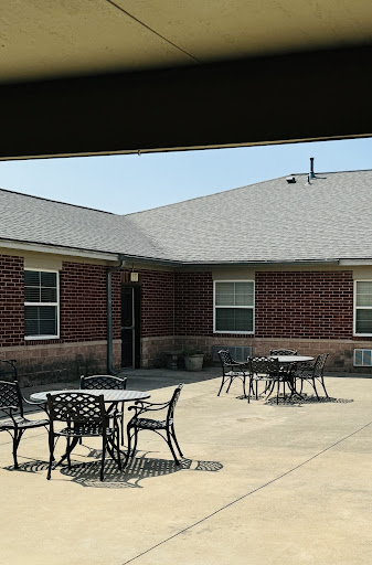 A view of a courtyard featuring outdoor tables and a brick building under clear skies.