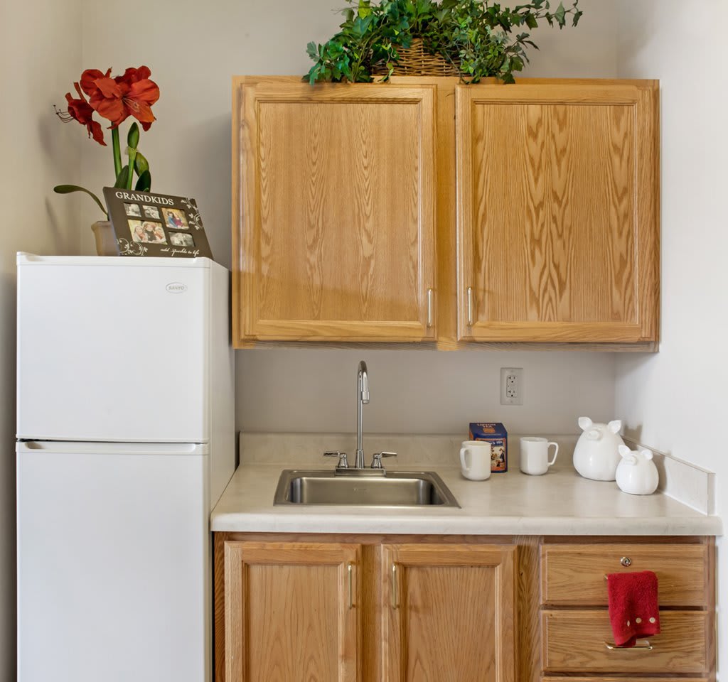 A small kitchen area with wooden cabinets, a white refrigerator, and countertop decor.