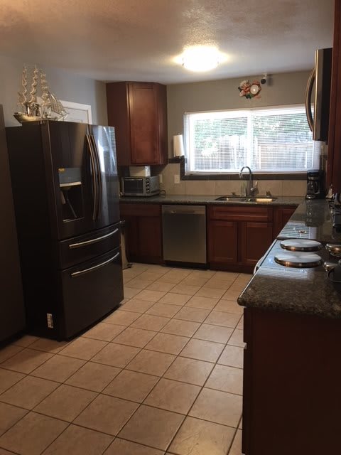 A modern kitchen with dark wood cabinets and stainless steel appliances.