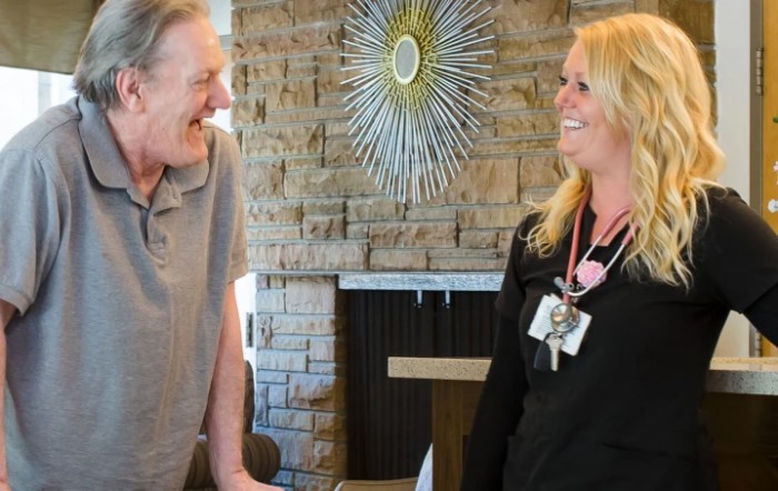 Two people smiling and engaging in conversation indoors.