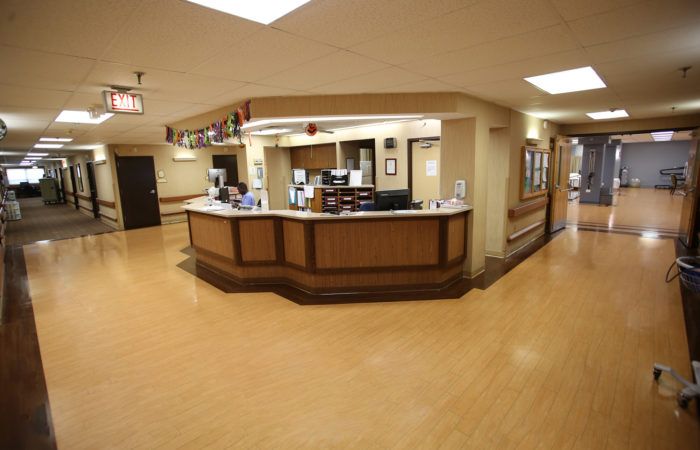 A hospital reception area featuring a central desk and surrounding hallway.