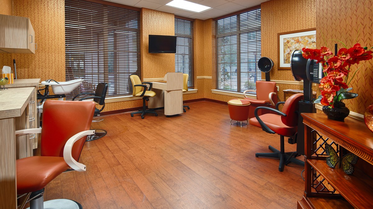 A modern salon interior with wooden flooring and multiple hairdressing chairs.