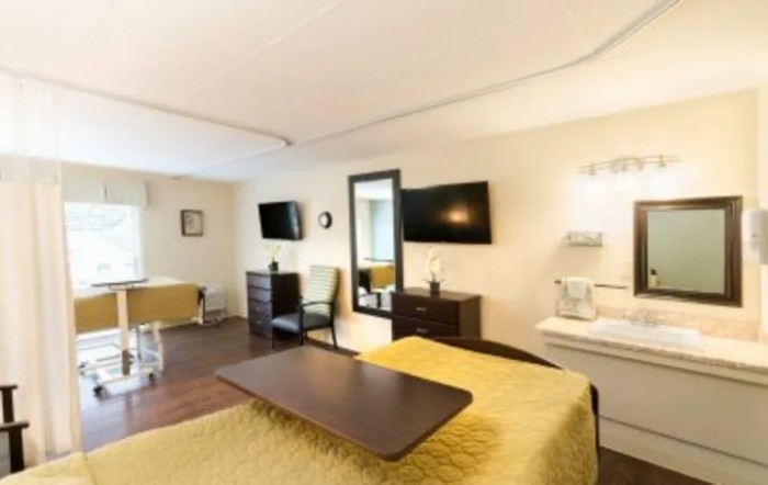 A well-lit hospital room featuring a bed, television, and comfortable furnishings.