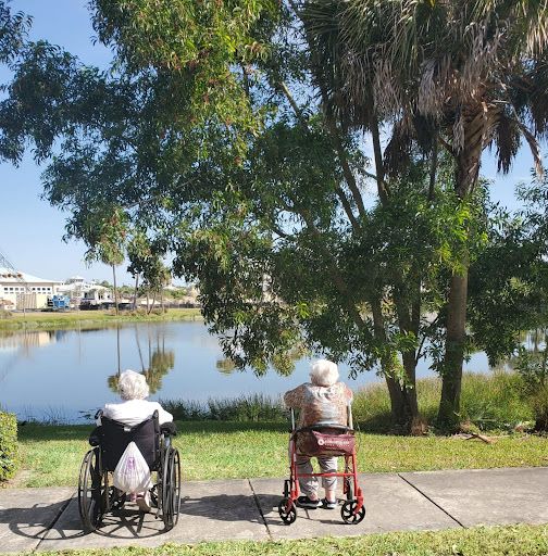 Two elderly individuals enjoying a peaceful moment by the lake in a beautiful park.