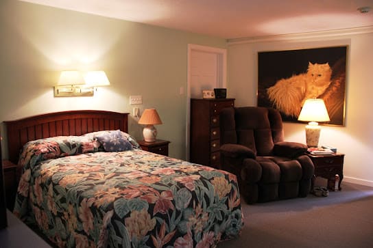 A cozy bedroom featuring a floral-patterned bedspread and warm lighting.