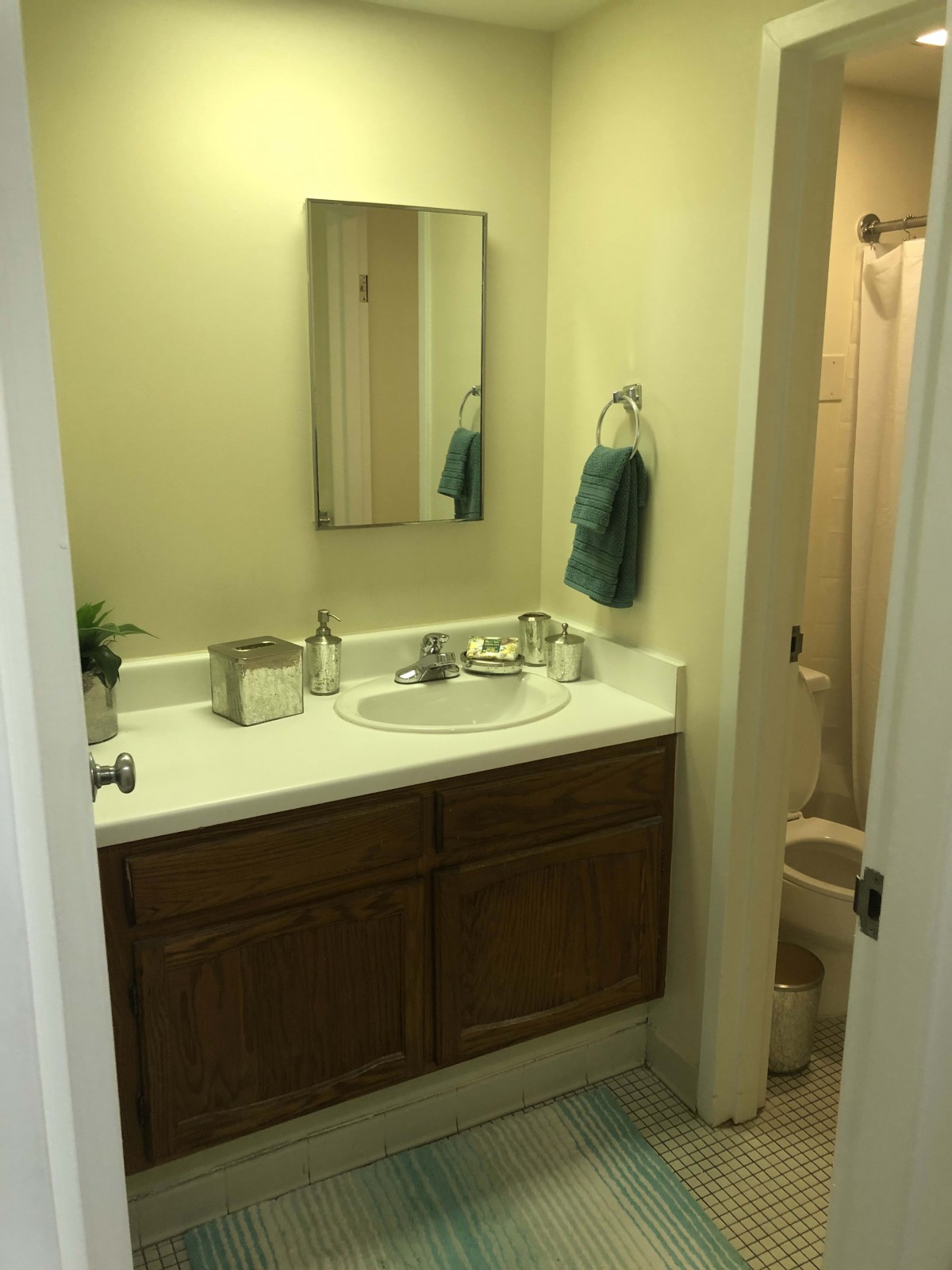 A small bathroom with a sink, mirror, and towel hanging on the wall.