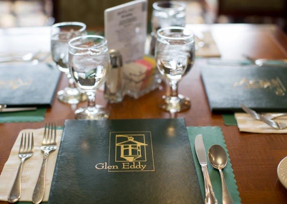 A restaurant table set with menus, glassware, and silverware.