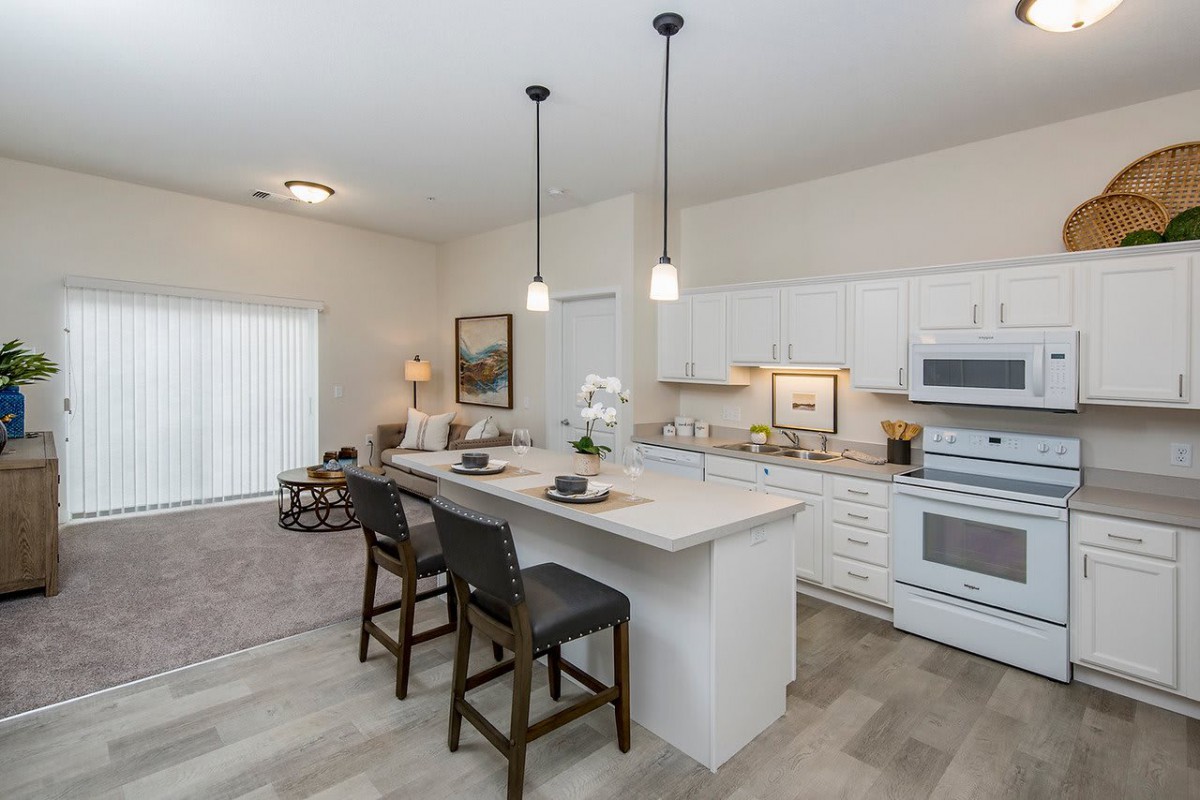 A modern kitchen with an island and bar stools, featuring sleek appliances and contemporary decor.